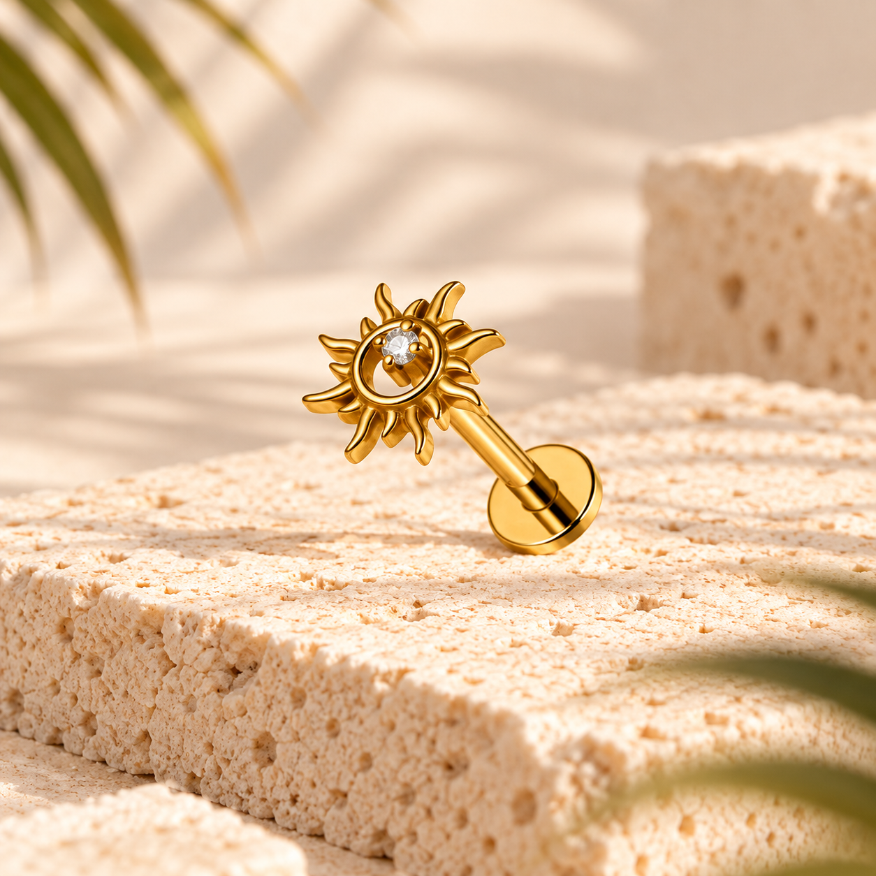 Stud flat back tournesol en titane doré avec zircon central, posé sur une pierre beige