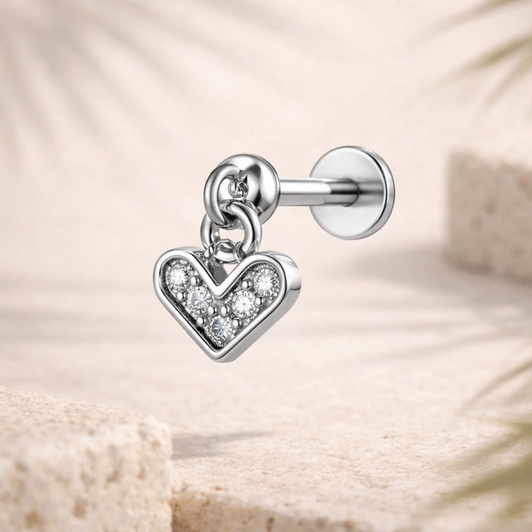 Stud flat back en acier avec pendentif cœur mobile serti de zircons blancs, posé sur une pierre claire