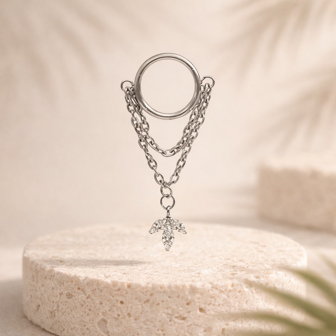 Anneau clicker en titane argenté avec double chaîne et pendentif feuille serti de zircons, sur pierre claire