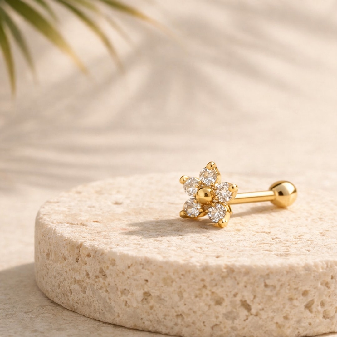 Stud de nez doré en forme de fleur à zircons blancs posé sur une pierre claire