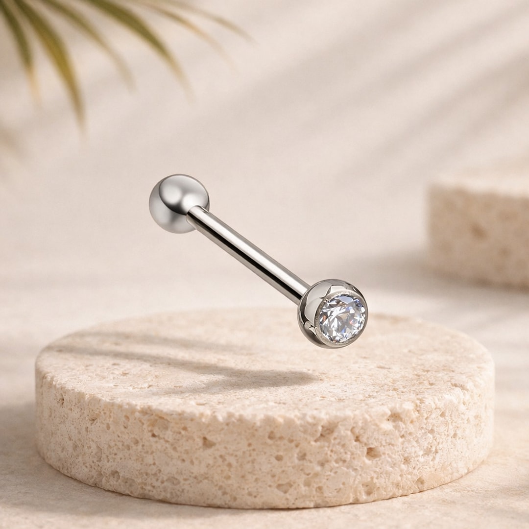 Barre de langue en titane poli avec bille lisse et zircon blanc rond serti, posée sur une pierre claire