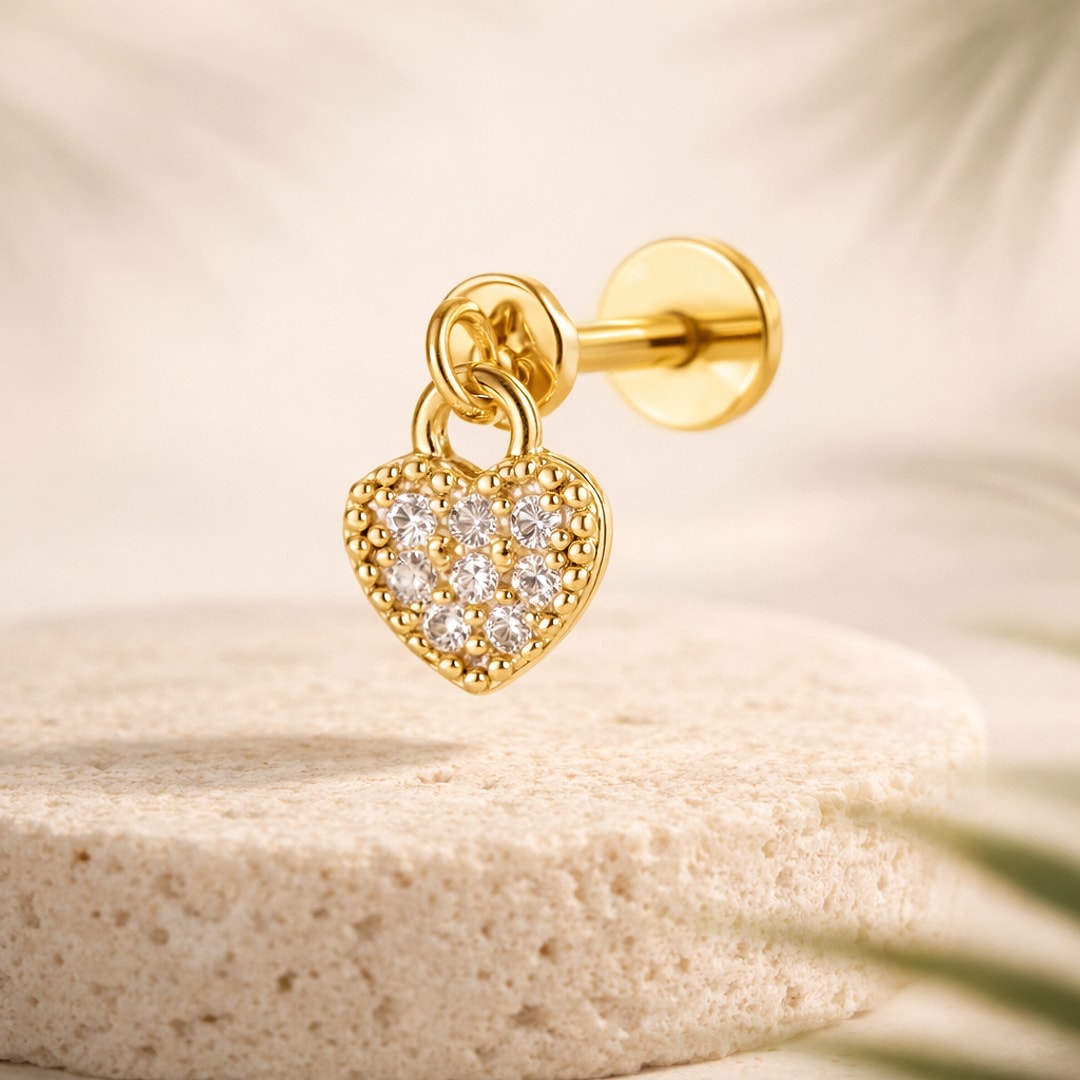 Stud flat back avec pendentif cœur pavé de pierres claires, tige à boule vissée, posé sur une pierre claire