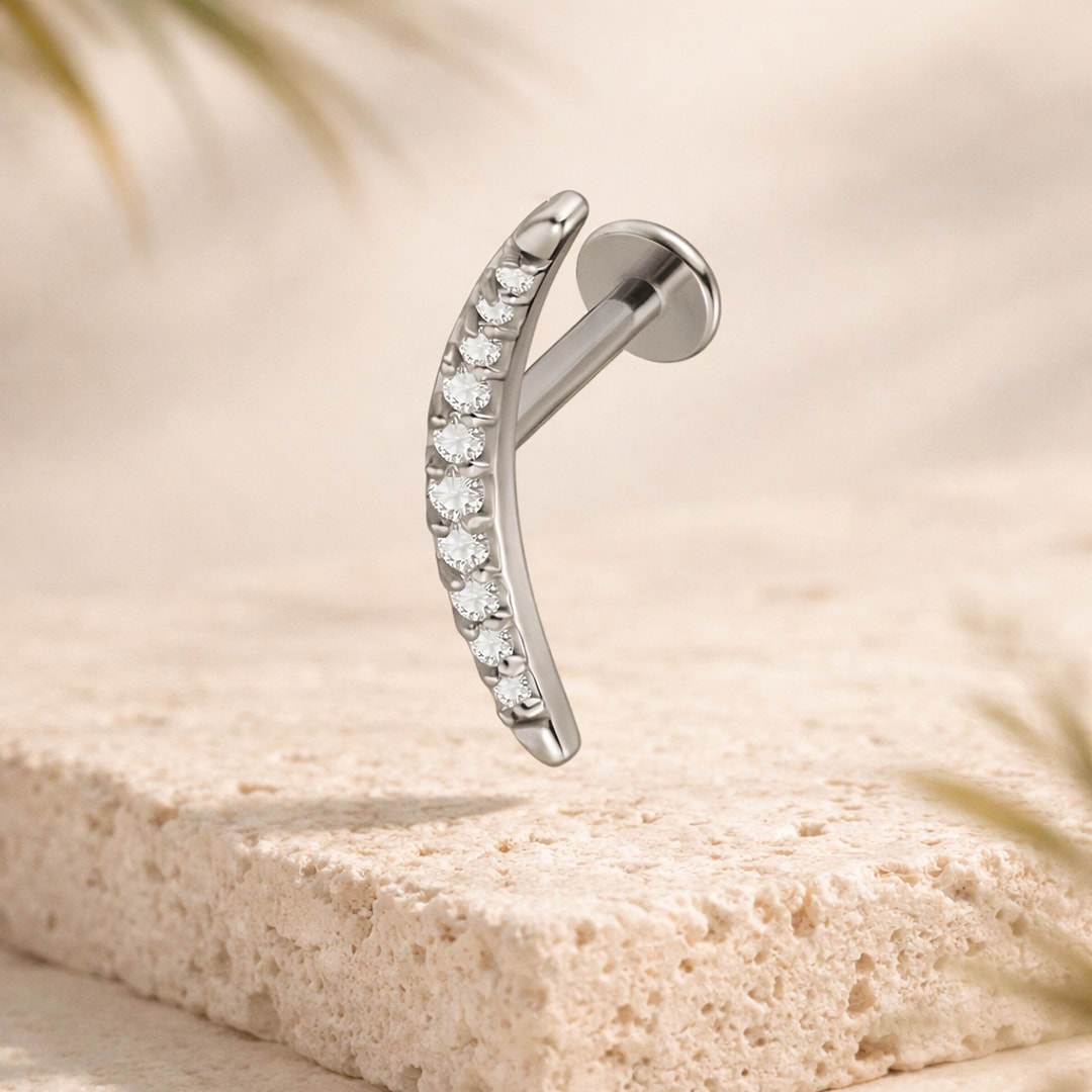 Labret acier argenté avec arc pavé de cristaux blancs, disque plat, posé sur une pierre claire