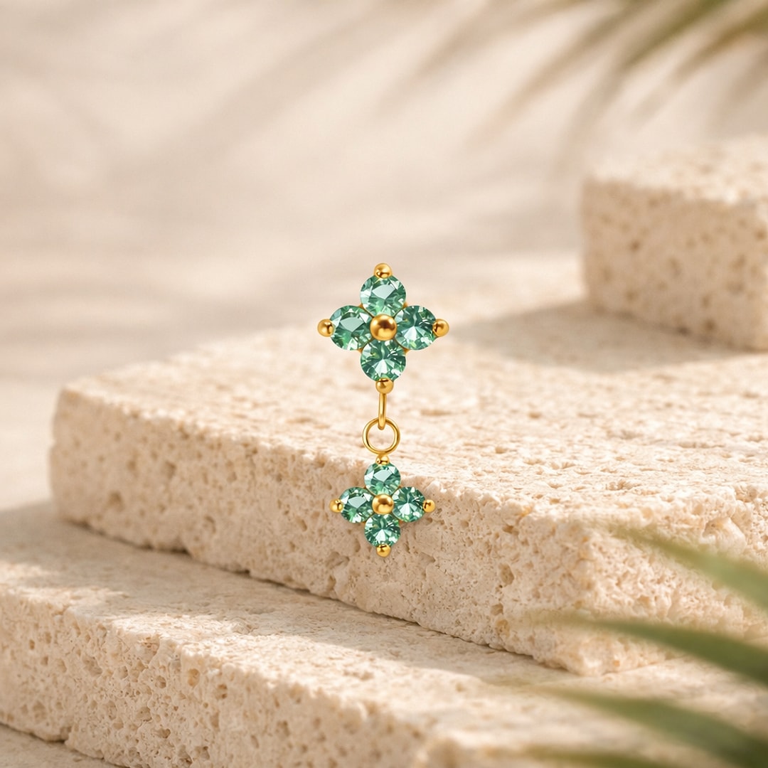 Top de piercing en titane doré, deux fleurs à quatre pétales serties de zircons verts, la seconde pendante