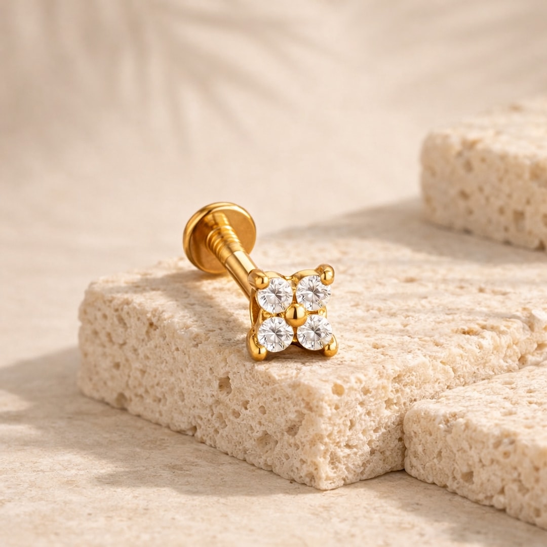 Labret doré à motif fleur de quatre zircons blancs posé sur une pierre claire