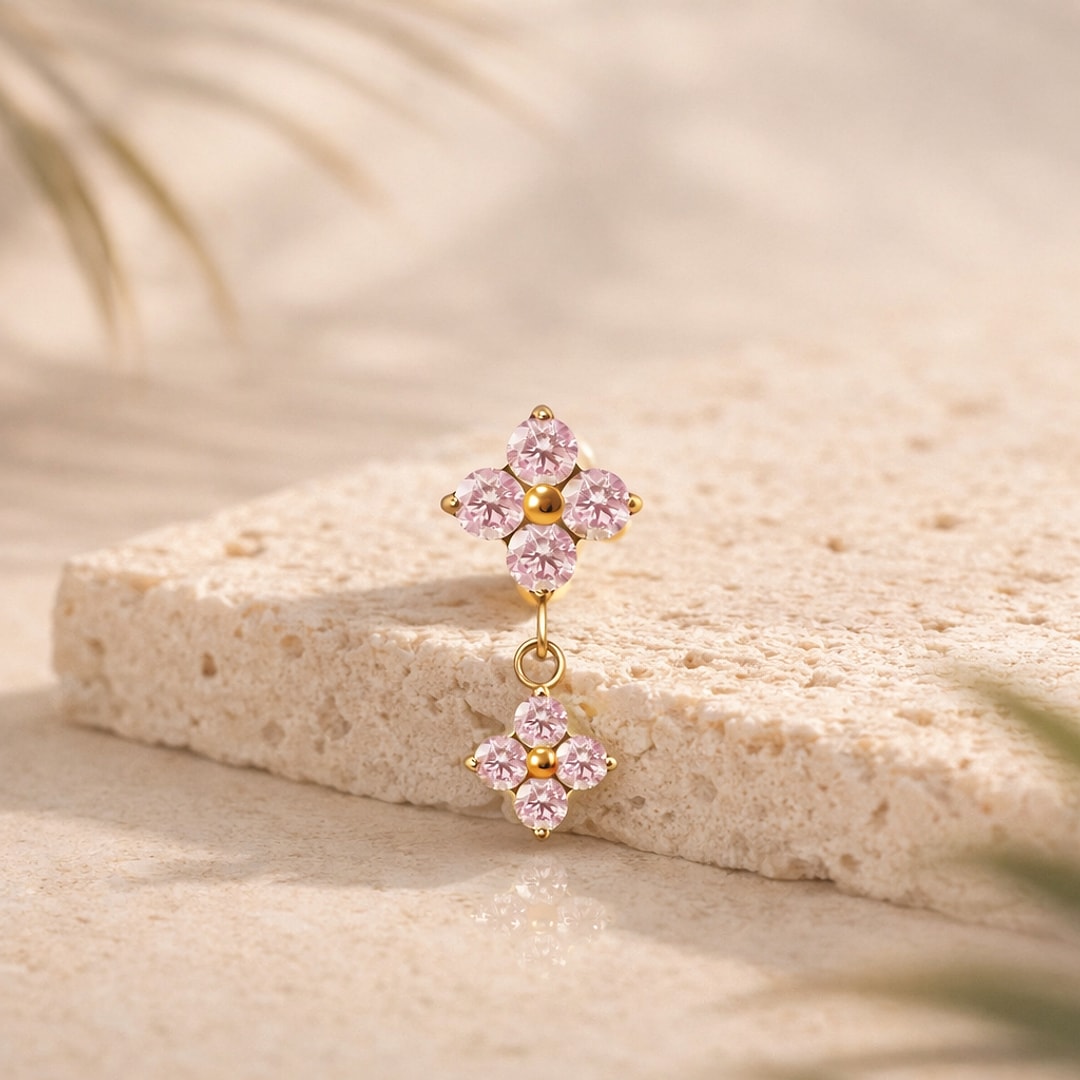 Top piercing titane doré composé de deux fleurs à quatre pétales en zircons roses, la seconde pendante