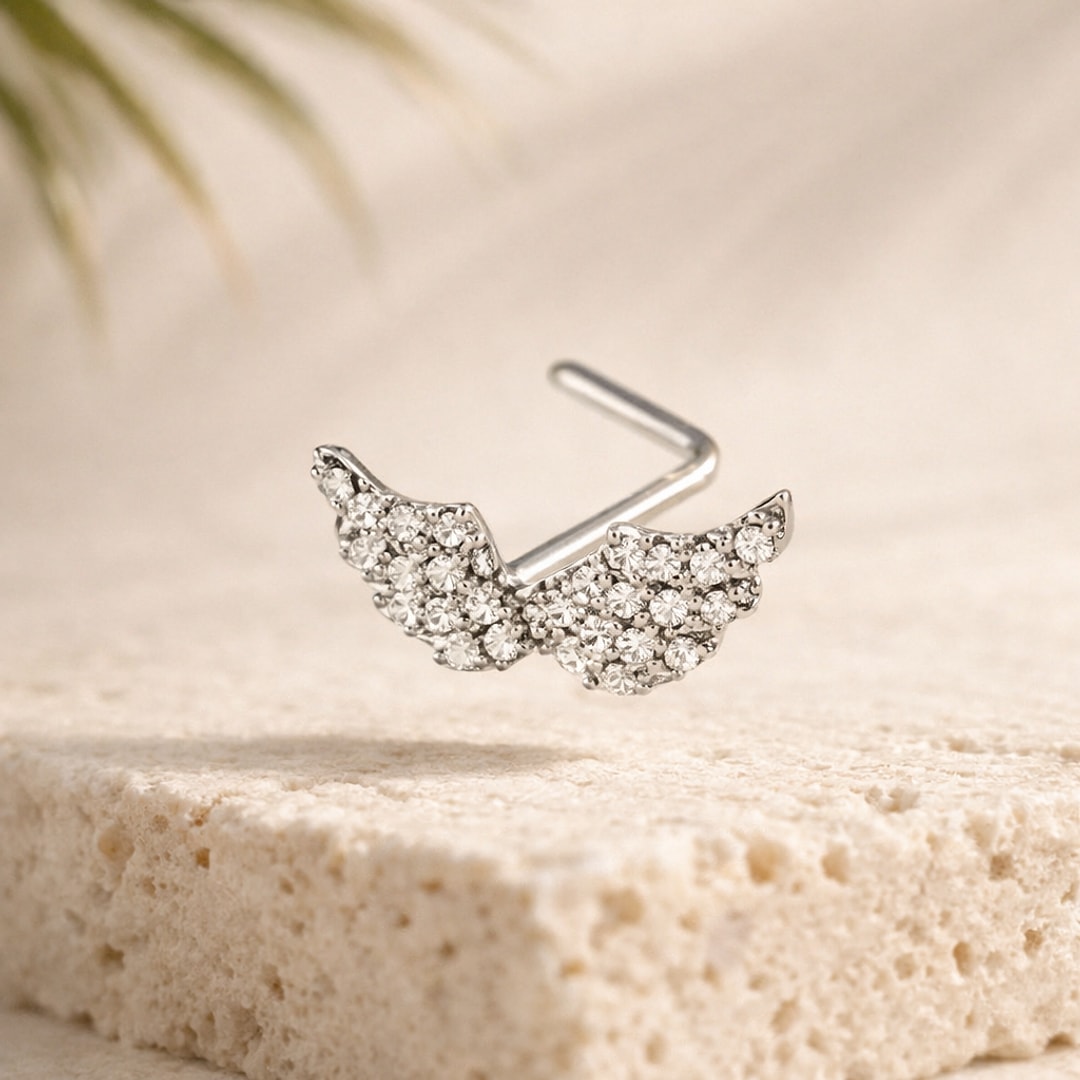 Stud de nez en L en acier argenté en forme d'ailes d'ange pavées de zircons, posé sur une pierre claire