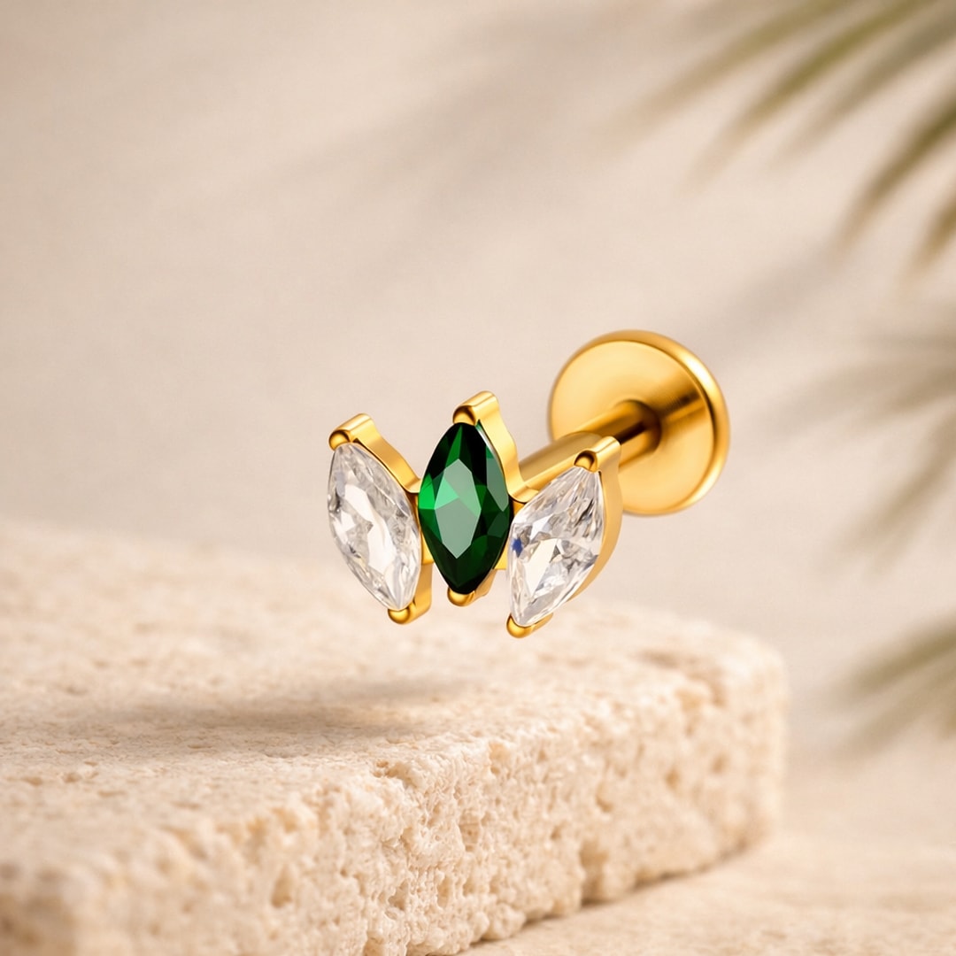 Stud flat back en titane doré orné de trois zircons marquise, un vert au centre et deux blancs, sur pierre claire
