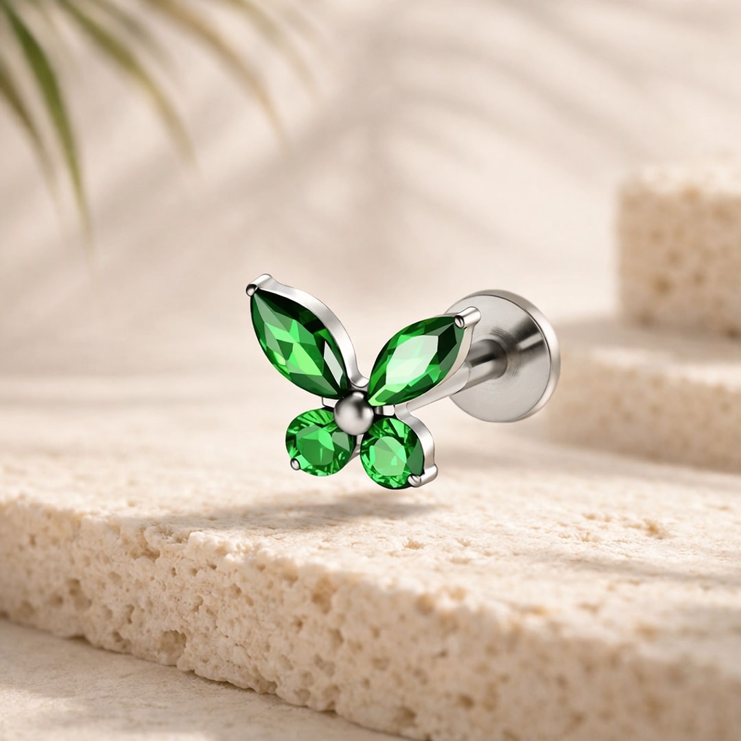 Stud flat back papillon en titane argenté serti de zircons verts marquise et ronds, posé sur une pierre claire