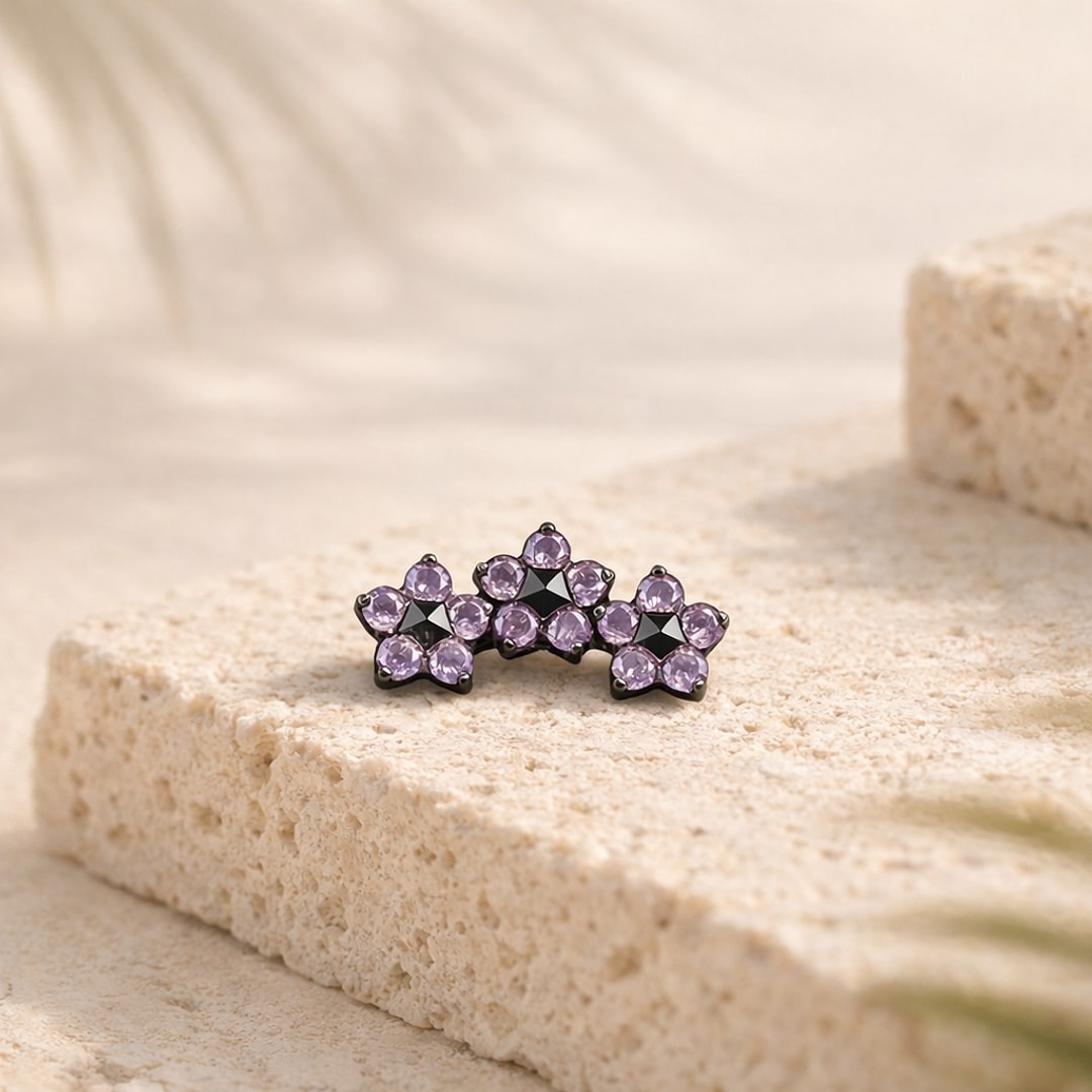 Stud de nez en titane noir à trois fleurs serties de zircons violets, posé sur une pierre claire