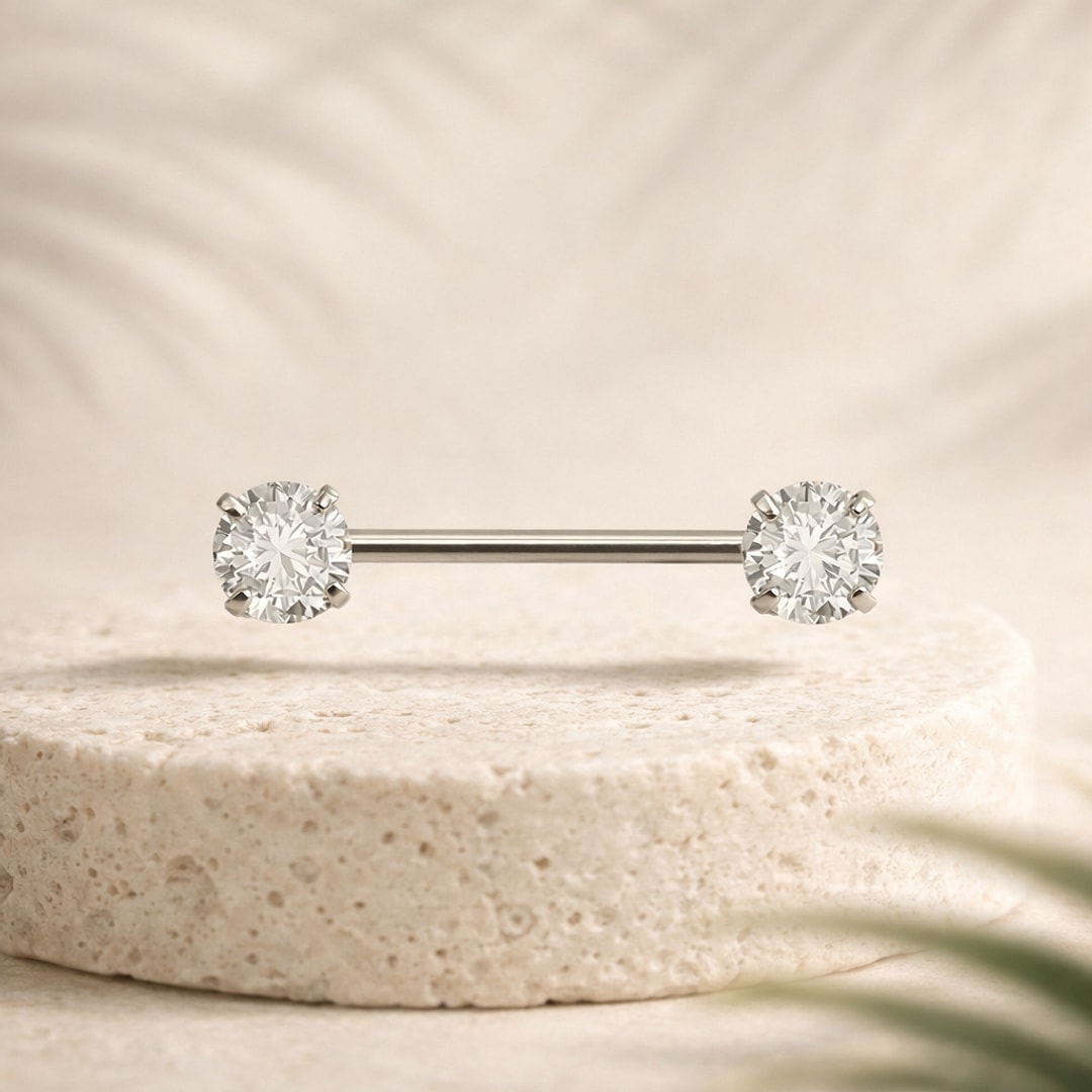 Barre de piercing téton en titane argenté avec deux zircons ronds sertis griffes sur socle de pierre claire