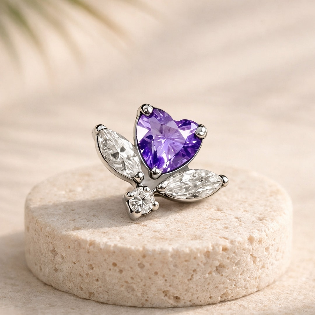 Top de piercing en titane argenté en forme de pétales, zircon violet cœur et zircons blancs navettes, posé sur une pierre claire