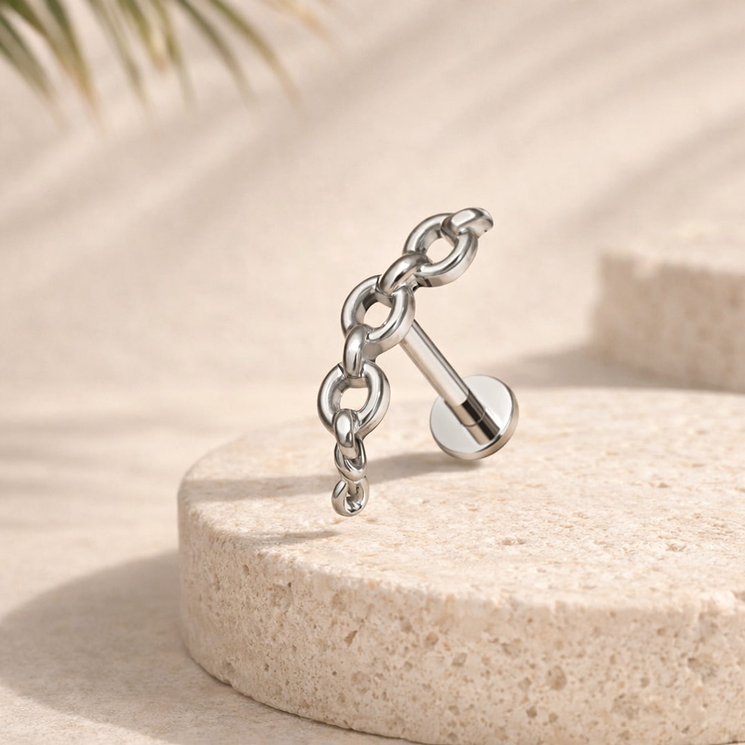 Stud flat back en titane argenté avec pendentif chaîne à maillons, posé sur une pierre beige