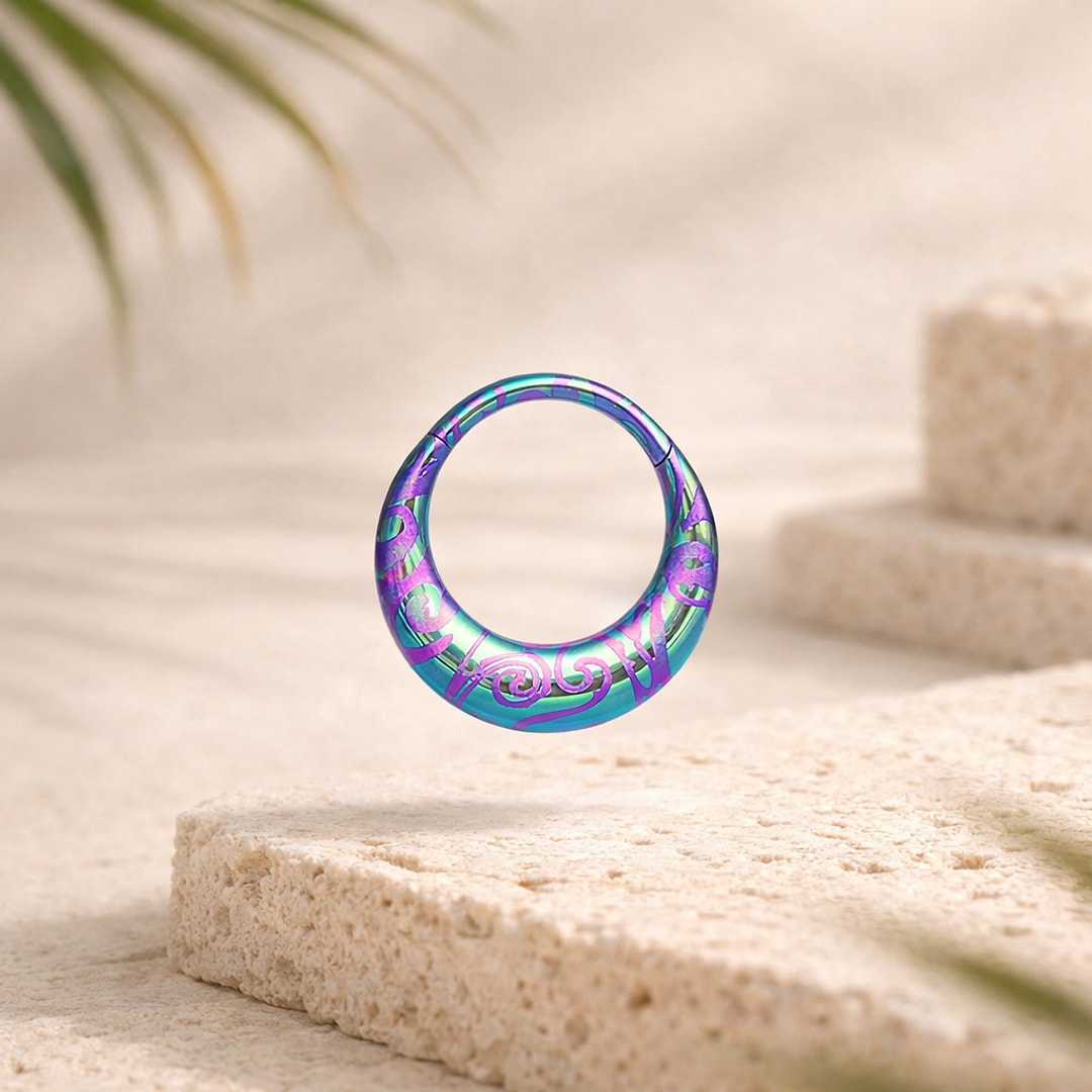 Anneau clicker en titane anodisé vert, bleu et violet avec spirales gravées, posé sur une pierre claire