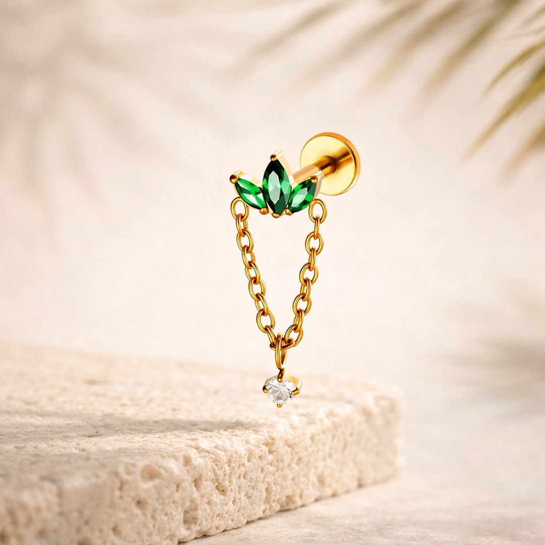 Labret titane doré avec trois zircons verts marquise et chaîne dorée terminée par un zircon blanc