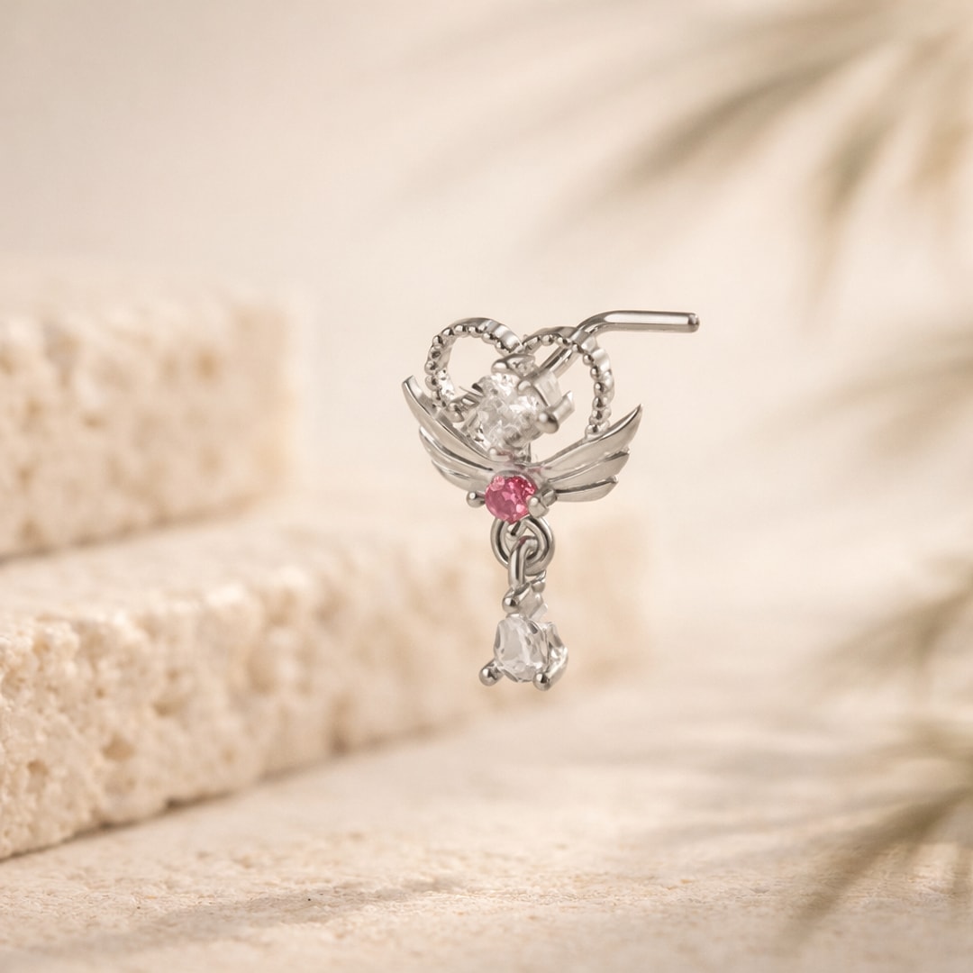 Stud de nez en L argenté : ailes, zircon blanc, pierre rose et pampille pendante sur fond beige