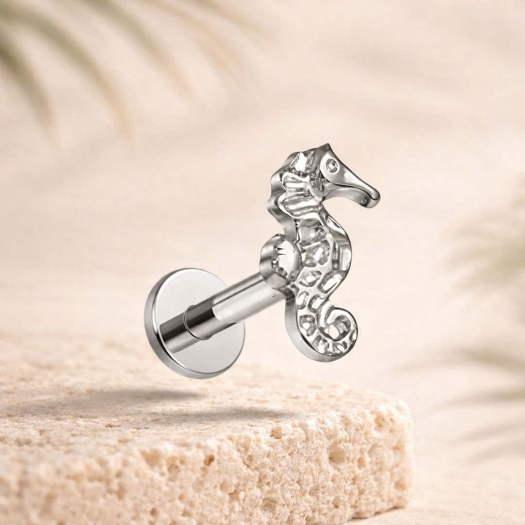 Stud flat back hippocampe argenté en titane, tige droite 1,2 x 8 mm, posé sur une pierre claire