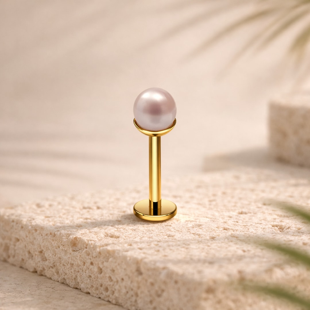 Stud flat back en titane doré avec fausse perle rose de 5 mm, posé sur une pierre claire