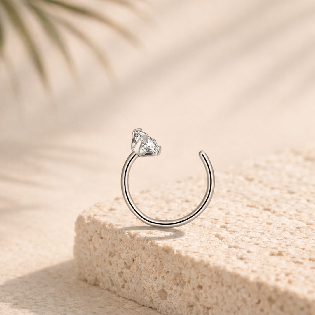 Anneau de nez ouvert en titane argenté avec zircon blanc taille goutte, posé sur une pierre claire