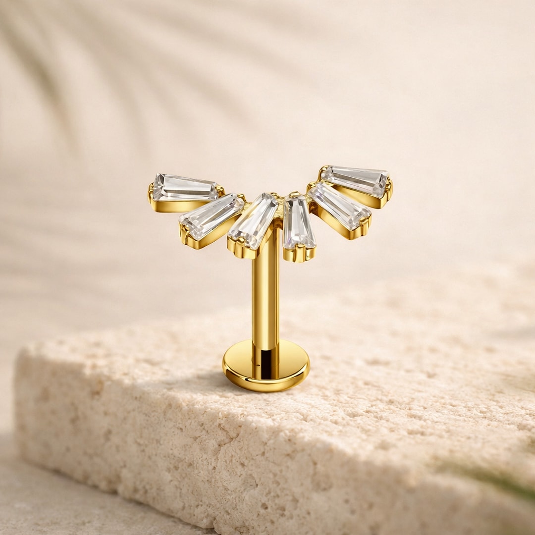 Stud flat back titane doré avec éventail de six zircons baguette blancs, posé sur une pierre claire