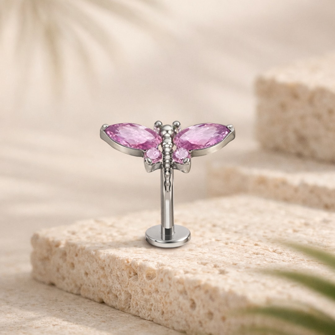 Stud flat back titane argenté en forme de papillon aux ailes serties de zircons roses, posé sur pierre claire