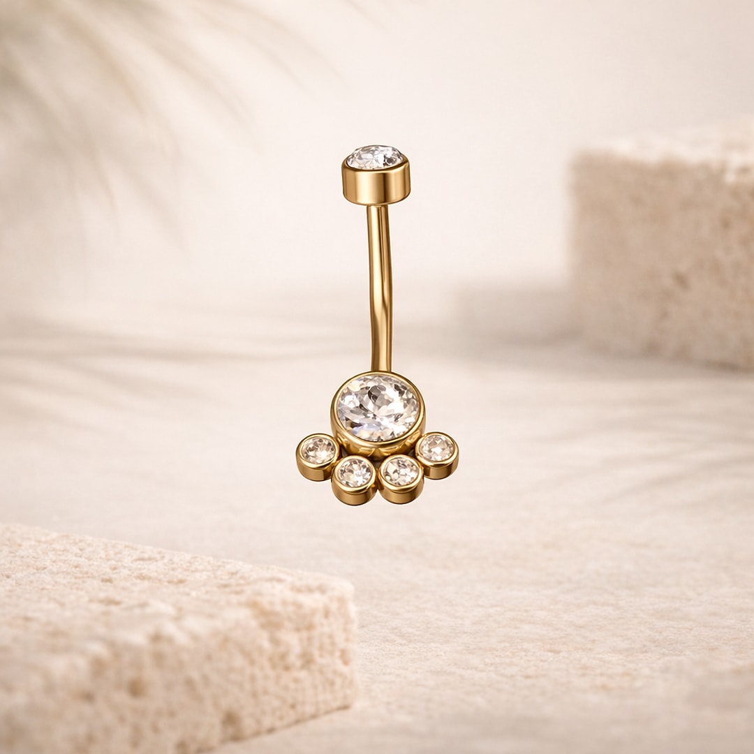 Banane de nombril dorée avec grand cristal et quatre petites pierres serties, sur fond beige