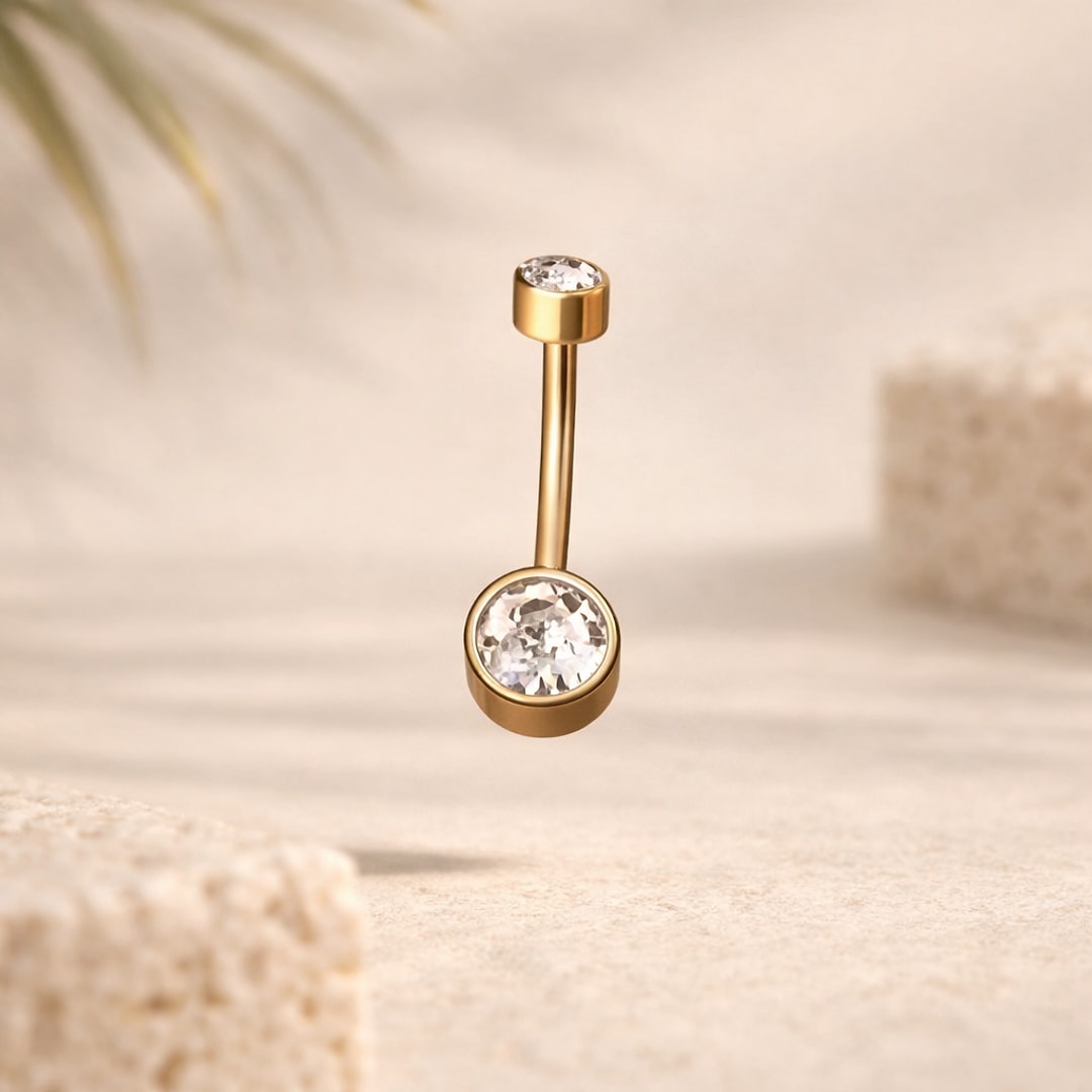 Banane de nombril dorée avec deux pierres cristal serties, tige courbée acier 1,2 × 8 mm, sur fond beige