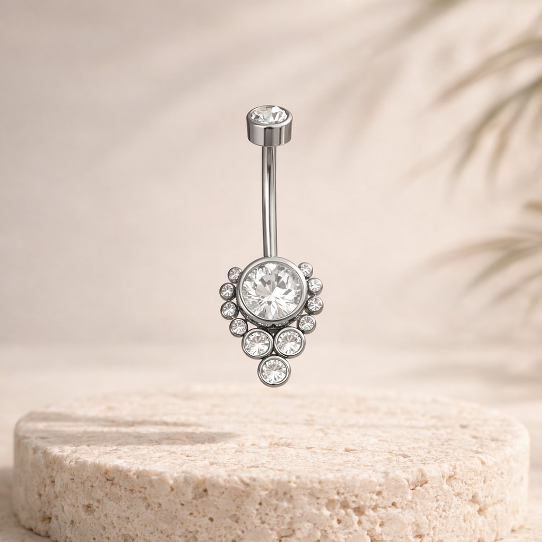 Banane de nombril en acier argenté, motif fleur de zircons blancs sertis, posée sur une pierre claire