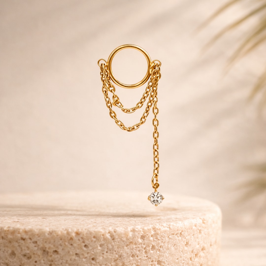Stud flat back en titane doré avec anneau, deux chaînes fines et zircon blanc pendant, posé sur pierre claire