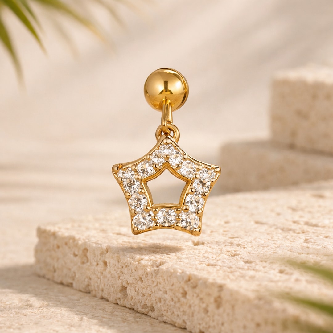Stud cartilage doré avec pendentif étoile ajourée serti de zircons blancs, posé sur une pierre claire