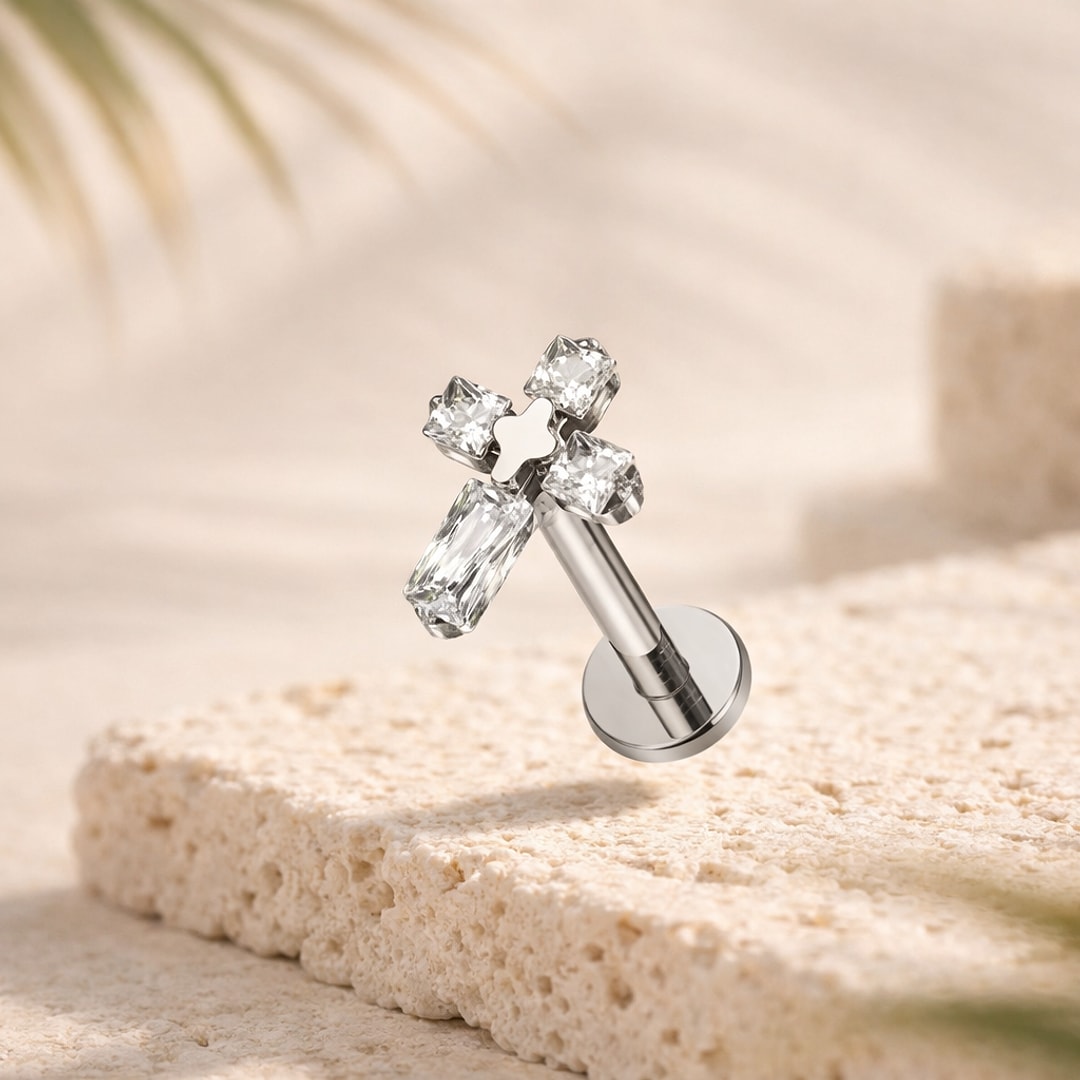 Stud flat back titane argenté en forme de croix sertie de zircons blancs, posé sur une pierre claire