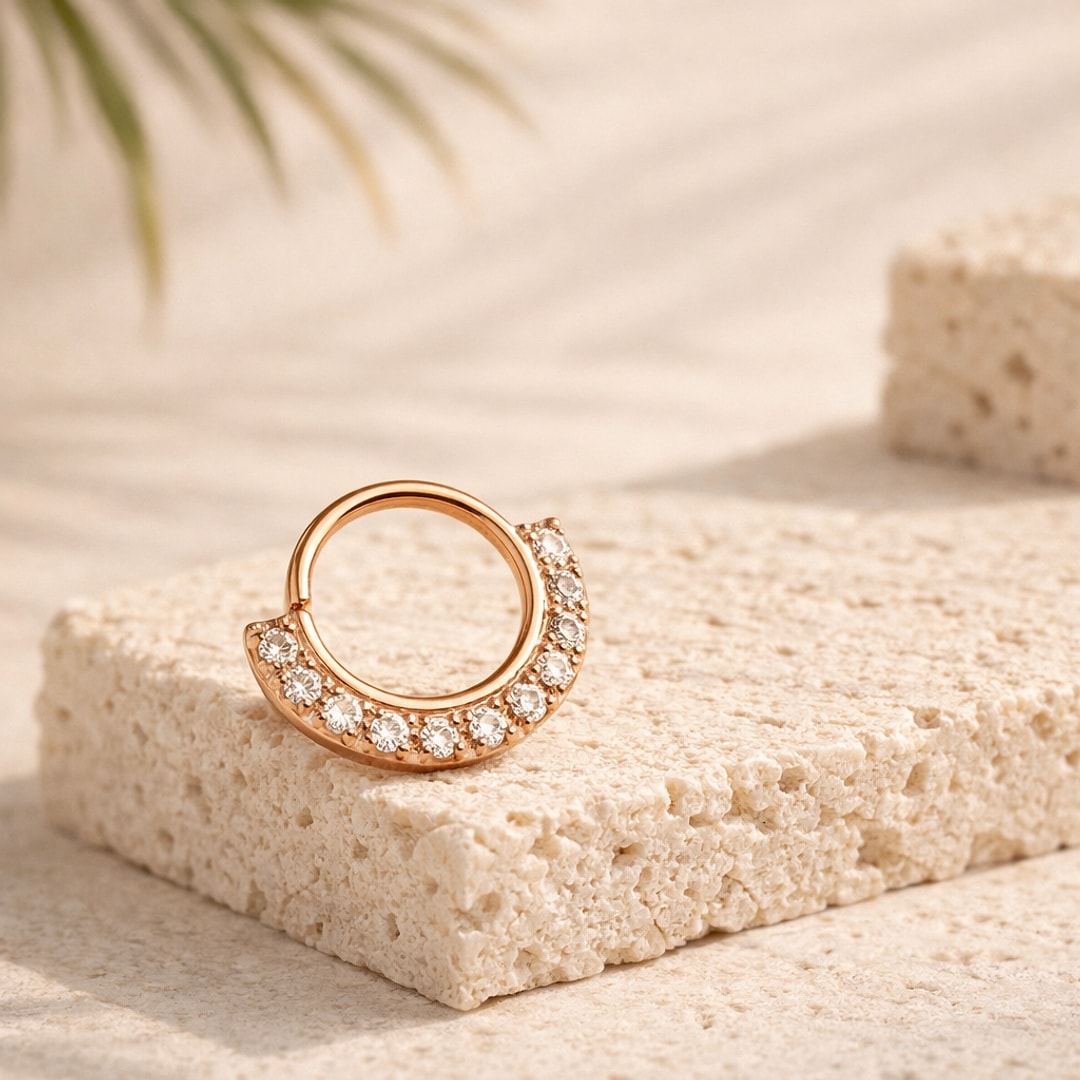 Anneau clicker de nez rose doré pavé de zircons blancs sur la moitié inférieure, posé sur une pierre claire