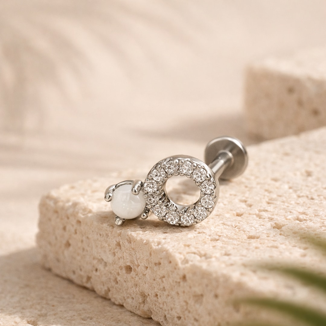 Labret flat back acier argenté avec cercle de zircons et cabochon blanc, posé sur une pierre claire