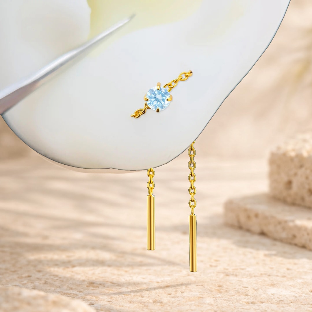 Chaîne d'oreille en titane doré avec zircon bleu serti et deux barrettes pendantes sur fond clair