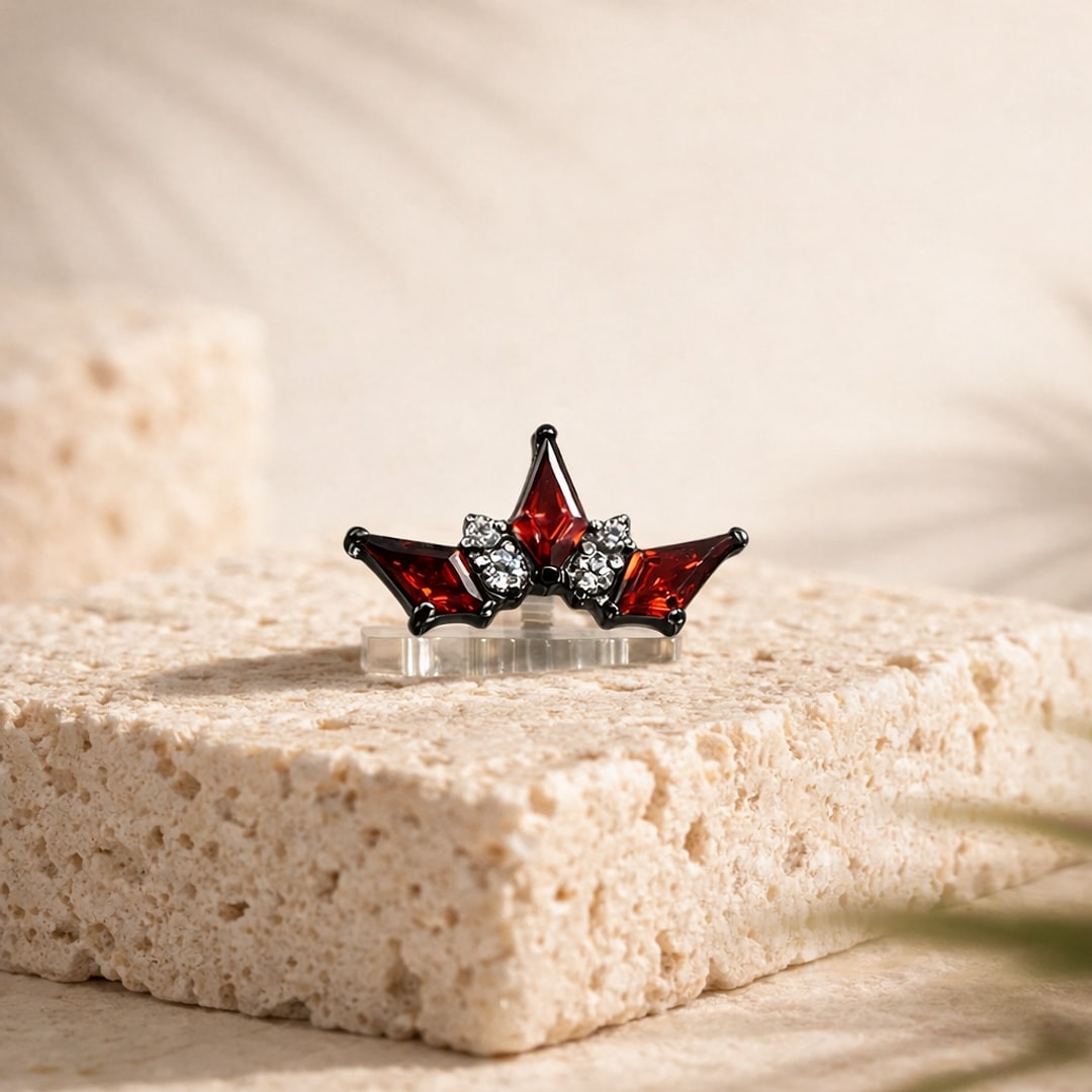Stud flat back en titane noir en forme de couronne, zircons rouges pointus et strass blancs, sur pierre claire