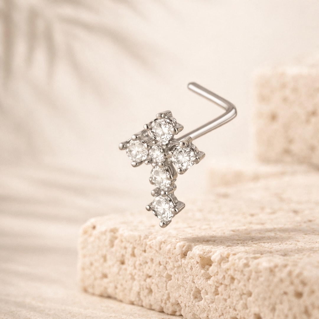 Stud de nez en L en acier argenté, motif croix serti de six zircons ronds, posé sur une pierre claire