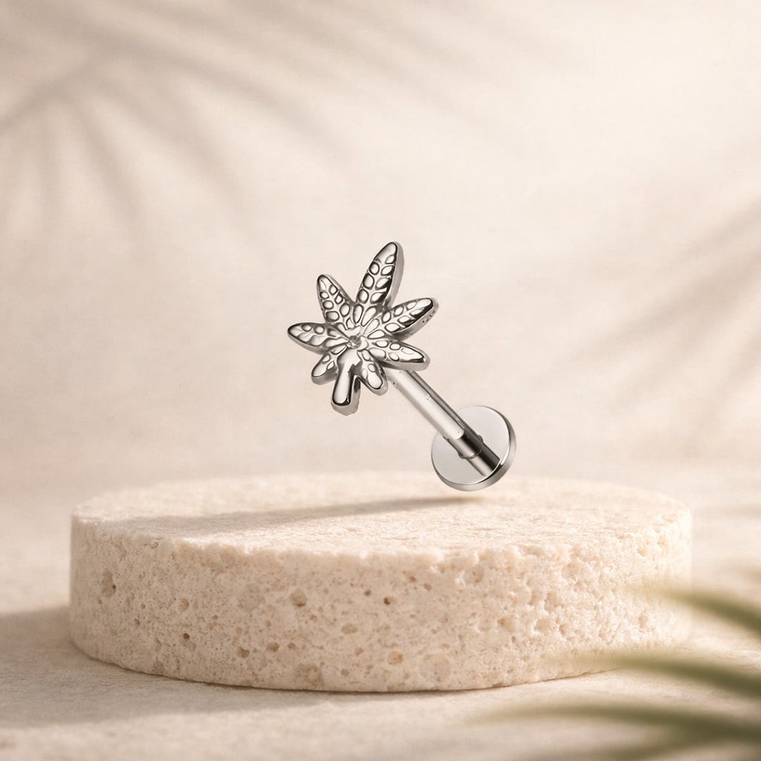 Labret flat back en titane argenté avec motif feuille ciselée aux nervures gravées, posé sur une pierre claire