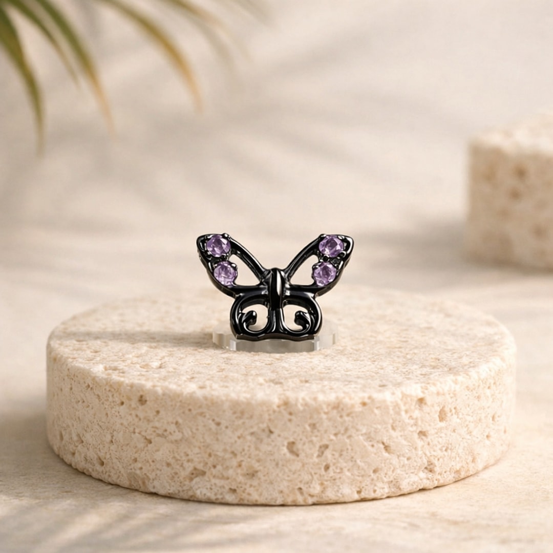 Stud de nez papillon en titane noir orné de quatre zircons violets, posé sur une pierre claire