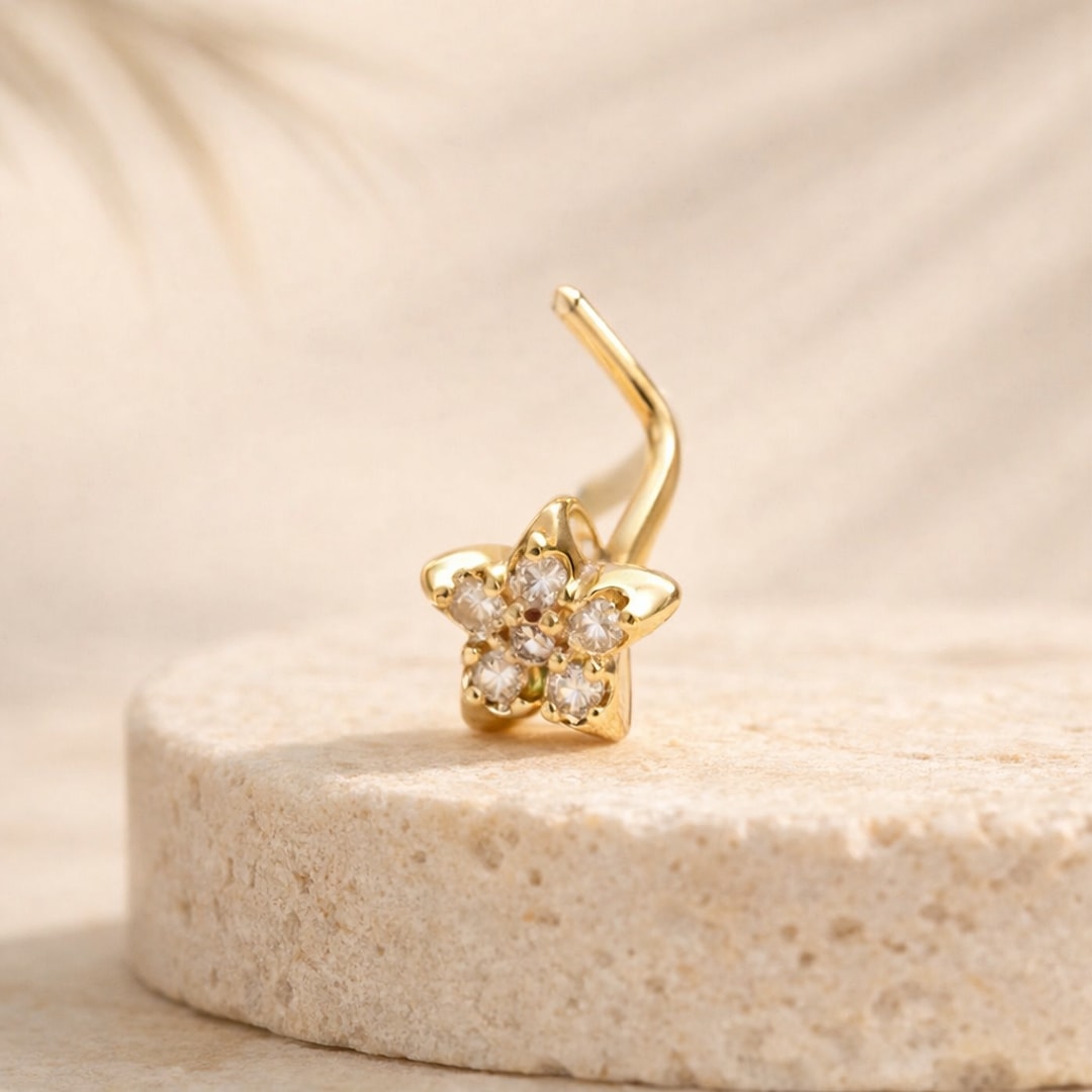 Nose stud doré en forme de fleur sertie de cinq zircons clairs, tige coudée, posé sur une pierre claire