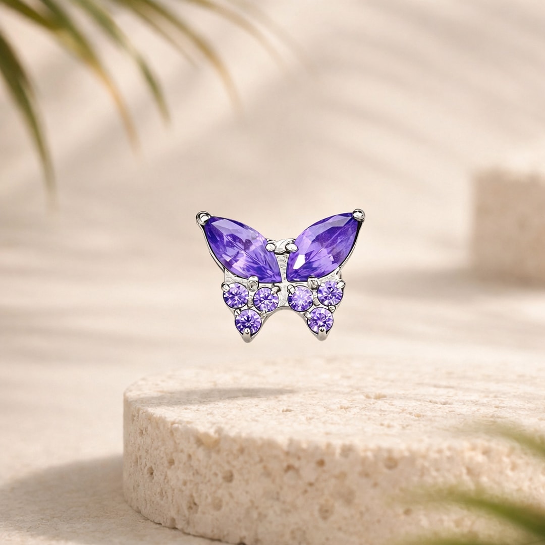 Top de piercing papillon en titane argenté serti de zircons violets, posé sur une pierre claire