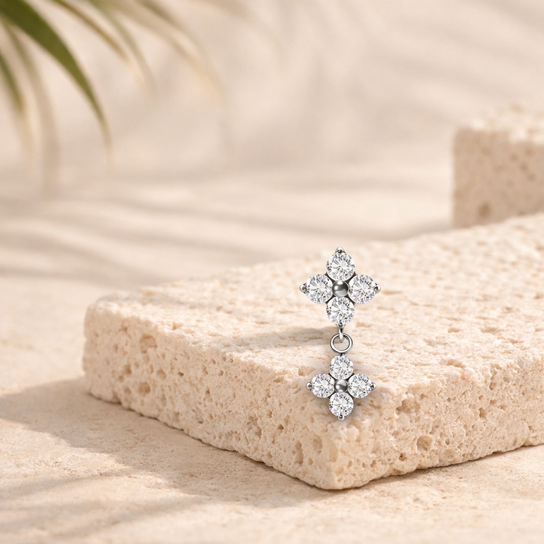 Top de piercing en titane argenté, fleur de zircons blancs avec seconde fleur pendante, posé sur une pierre claire