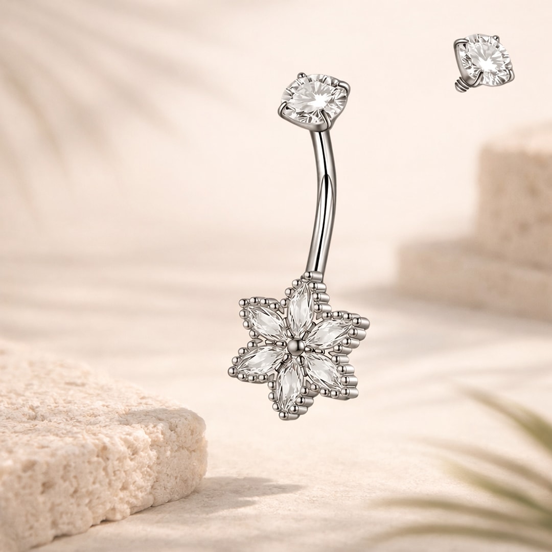 Piercing nombril acier argenté, fleur à six pétales en cristaux blancs et pierre ronde sur la boule du haut