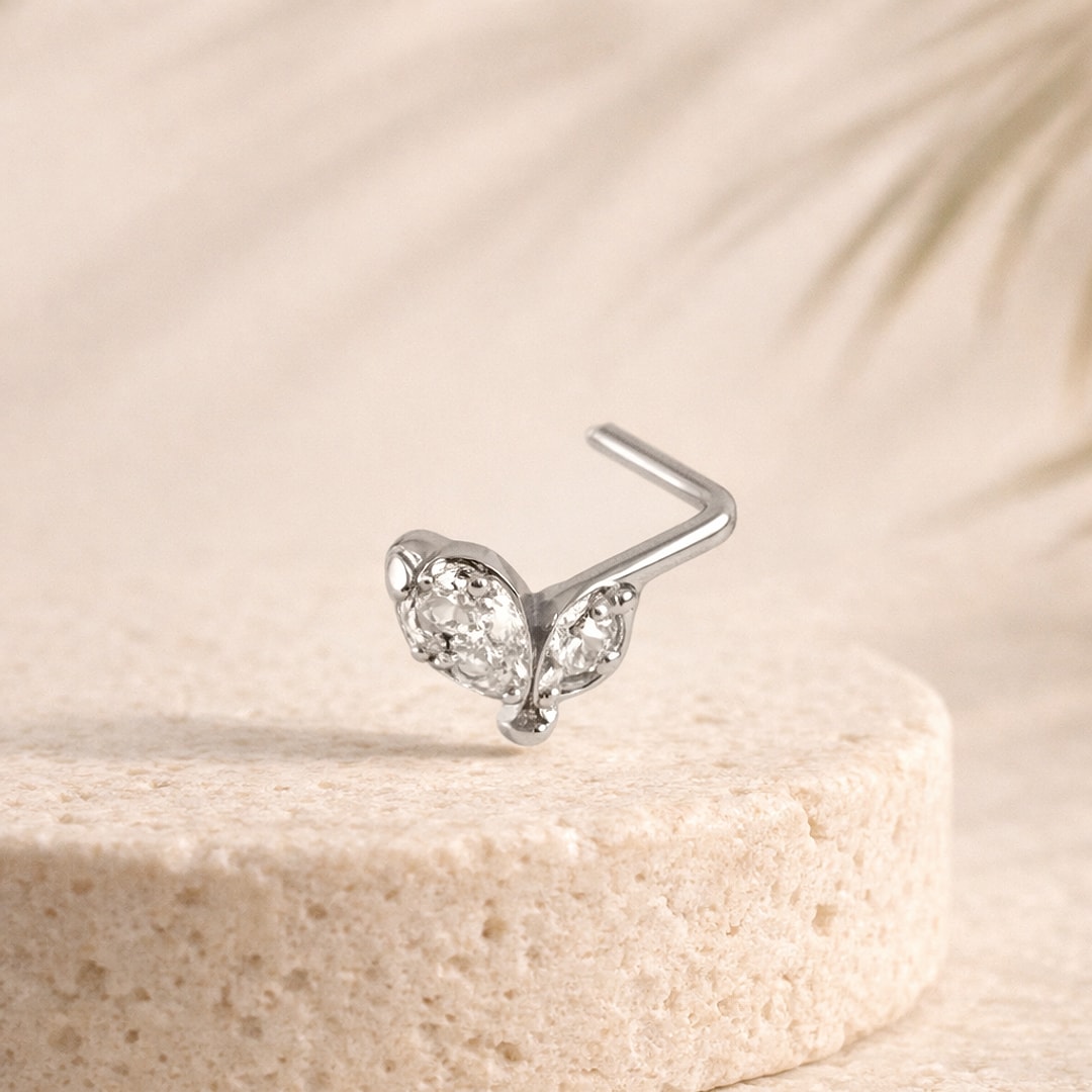 Stud de nez en L acier argenté, motif papillon serti de zircons blancs, posé sur une pierre claire