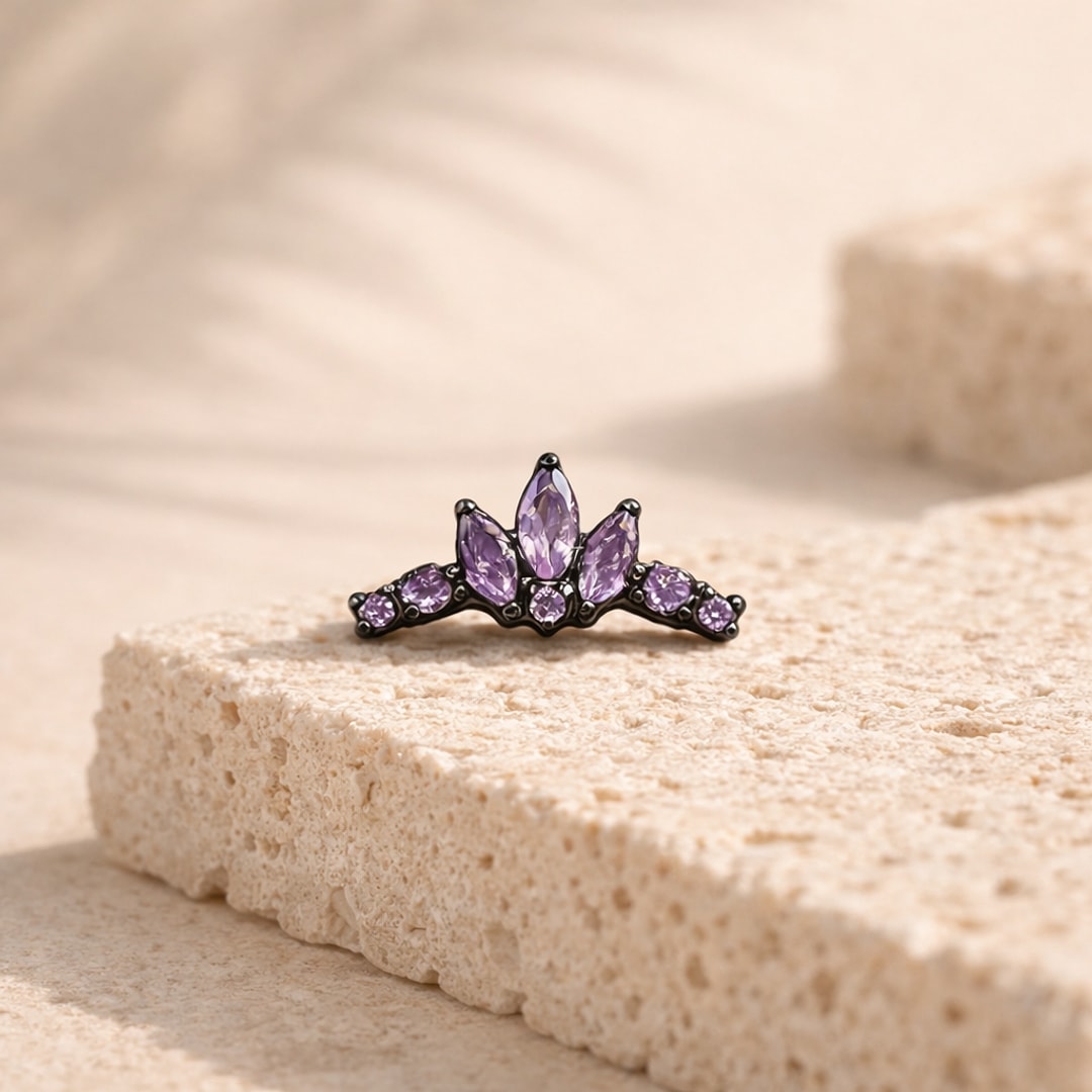 Stud flat back titane noir en forme de couronne sertie de zircons violets marquise, posé sur une pierre claire