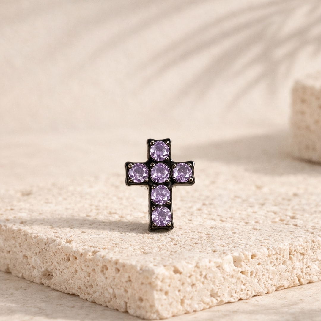 Stud flat back croix en titane noir serti de six zircons violets, posé sur une pierre claire