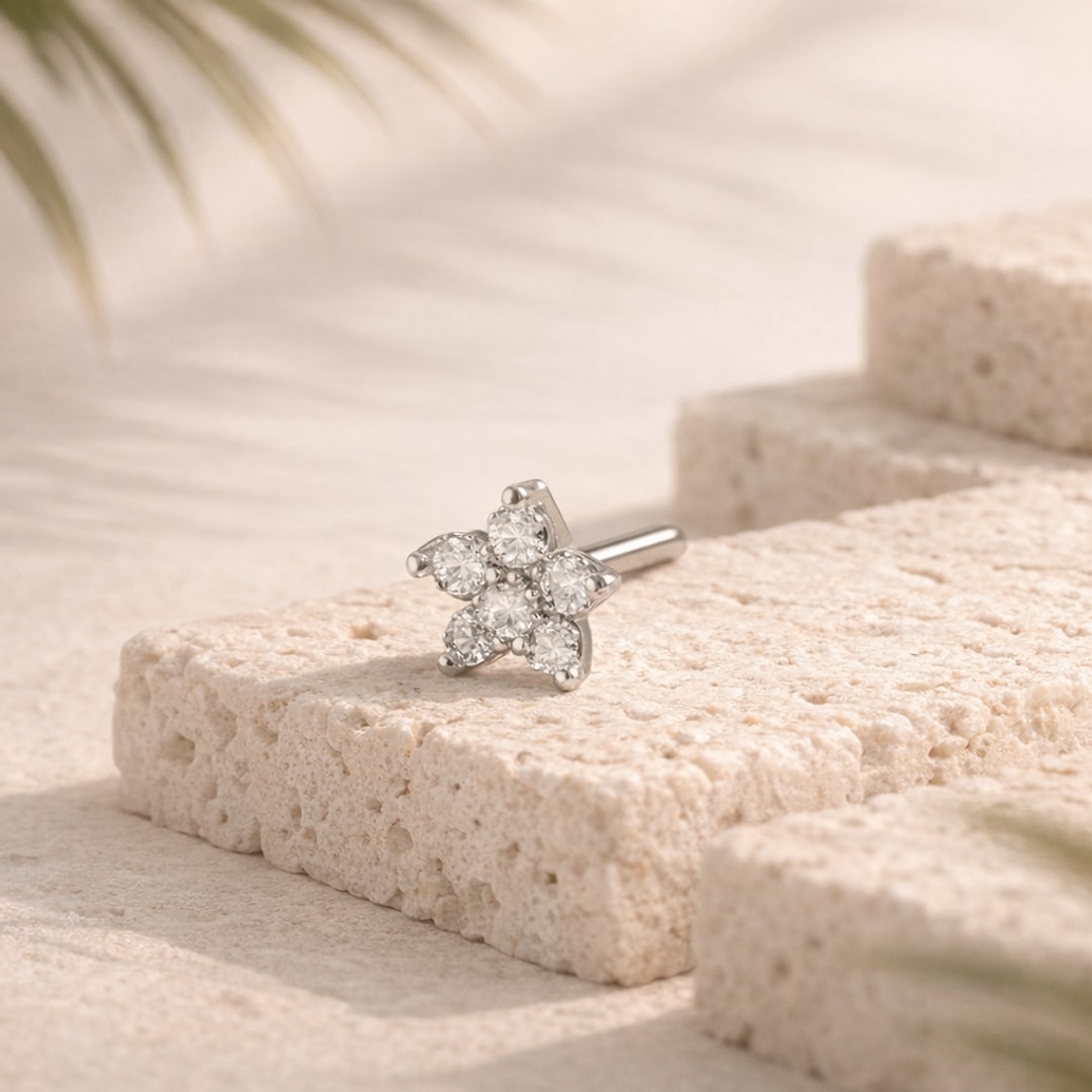 Stud de nez en L acier argenté avec fleur de cinq zircons posé sur une pierre claire