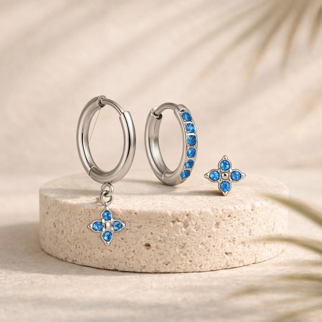 Lot de 3 bijoux d'oreille en acier : créole à pendentif fleur, créole sertie et puce fleur, zircons bleus