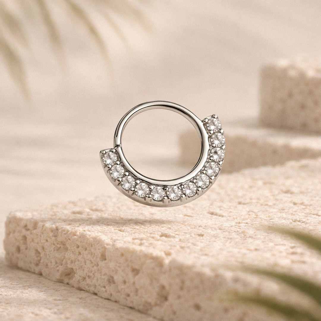 Anneau clicker de nez en acier argenté serti d'une demi-couronne de zircons blancs, posé sur pierre claire