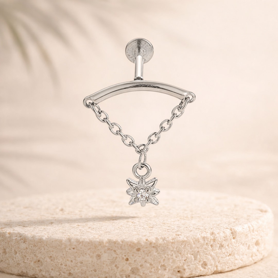 Labret acier argenté à chaînette avec pendentif étoile serti d'un zircon, posé sur une pierre claire