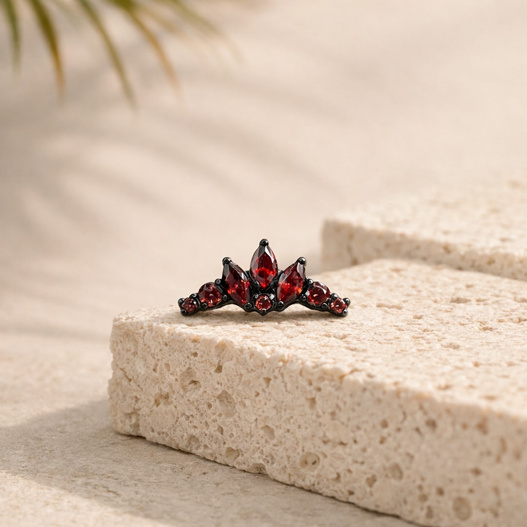 Stud flat back en titane noir orné d'une couronne de zircons rouges marquise et ronds, posé sur une pierre claire